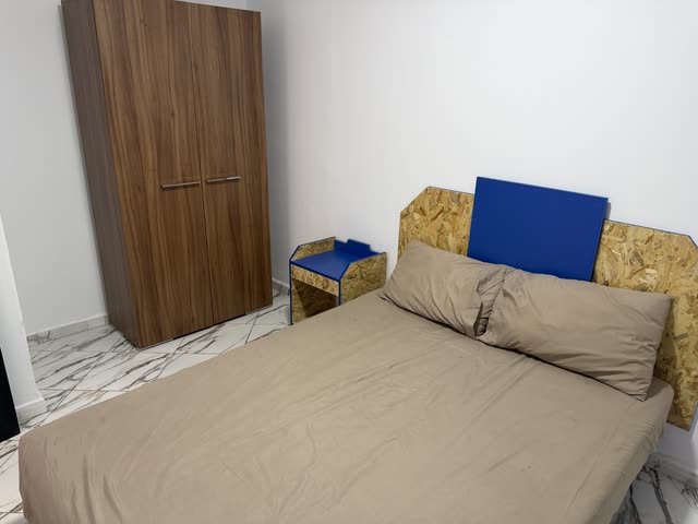 Chambre d'un duplex : lit double, armoire en bois foncé, tête de lit et chevet sur mesure, sol en marbre clair.